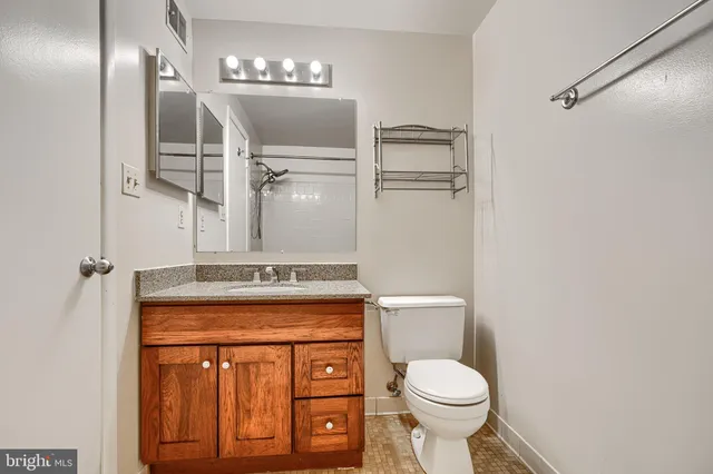 a bathroom with a granite countertop toilet sink and mirror