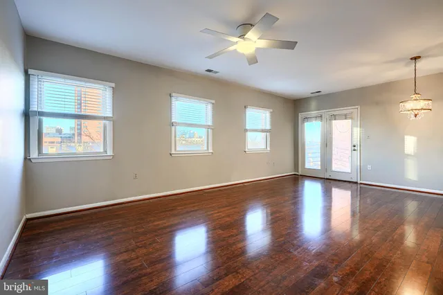 a view of an empty room with a window and wooden floor