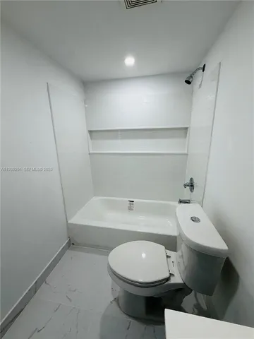 a white toilet sitting next to a bath tub
