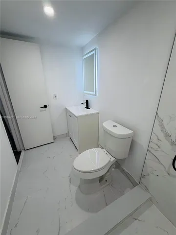 a white toilet sitting next to a bathroom sink and vanity