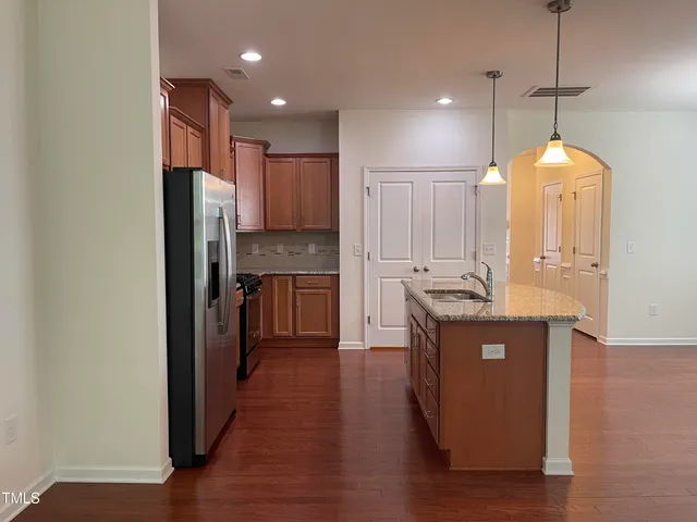 a kitchen with kitchen island granite countertop a sink cabinets and wooden floor