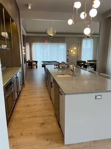 a large kitchen with kitchen island a large counter space a sink a window and stainless steel appliances