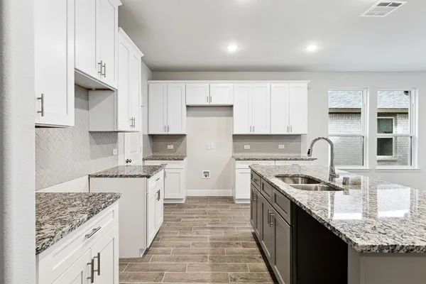 a kitchen with stainless steel appliances granite countertop a stove top oven a sink dishwasher and refrigerator with wooden floor