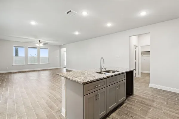 a kitchen with stainless steel appliances granite countertop a sink a stove and a wooden floors