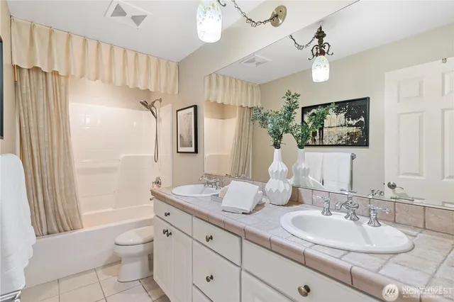 a bathroom with double vanity sink a mirror a light fixture and a shower