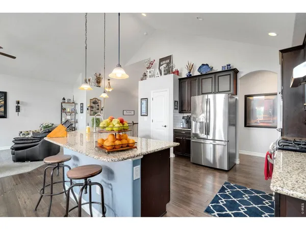 a kitchen with stainless steel appliances kitchen island granite countertop a refrigerator a stove a sink and dishwasher