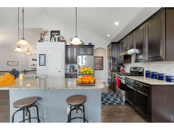 a kitchen with stainless steel appliances kitchen island granite countertop a sink cabinets and wooden floor