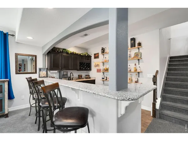 a kitchen with stainless steel appliances kitchen island granite countertop a dining table chairs and a refrigerator