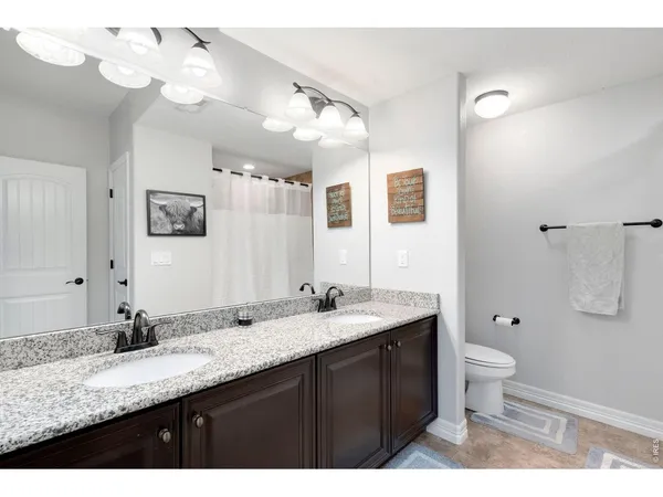 a bathroom with a granite countertop double vanity sink mirror and toilet