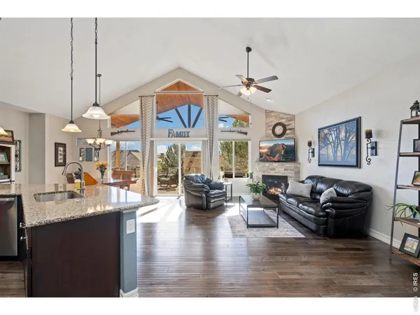 a living room with furniture kitchen area and a chandelier