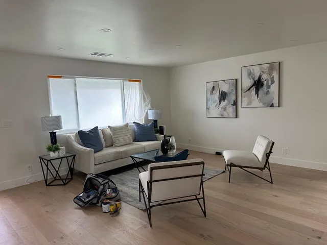 a living room with furniture a couch and a potted plant on table with wooden floor