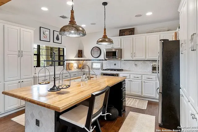 a kitchen with stainless steel appliances granite countertop a sink a stove a refrigerator and cabinets