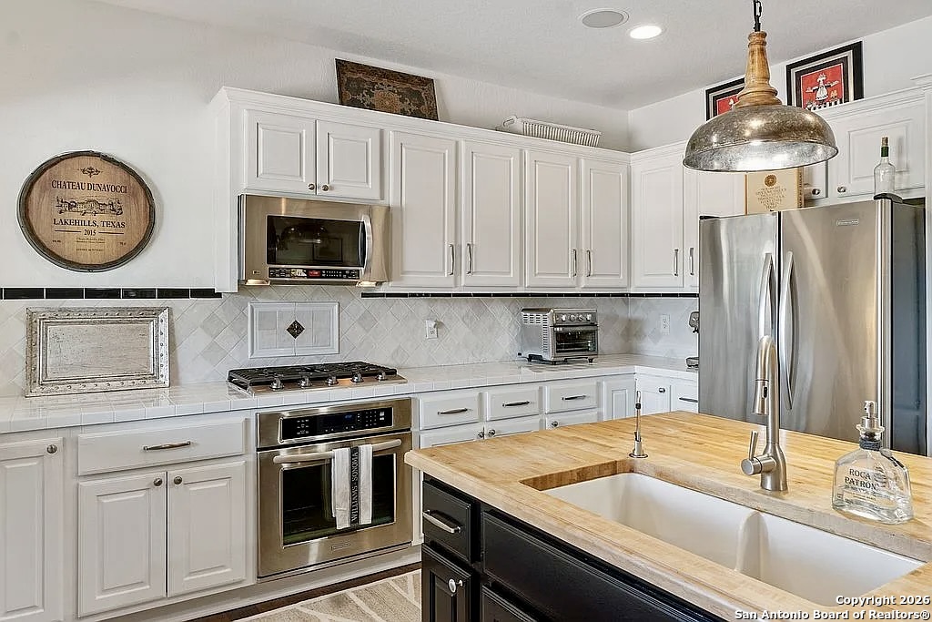1112 Kendall Jackson Comfort, TX 78013 - Photo 18 of 32 a kitchen with stainless steel appliances granite countertop a sink a stove and refrigerator