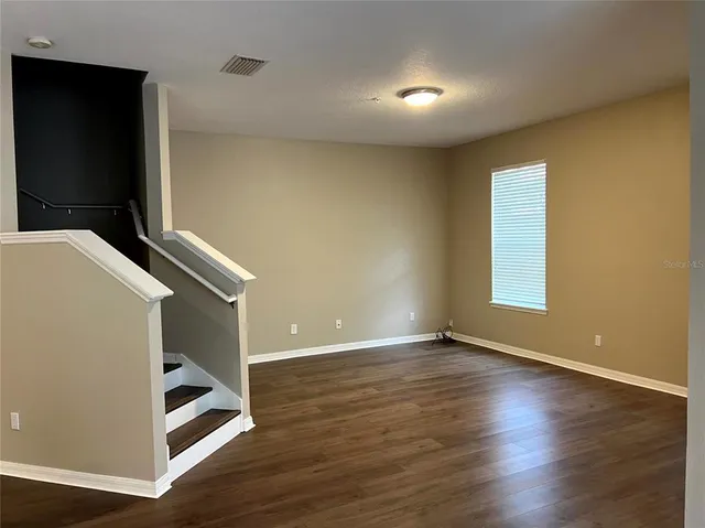 a view of an empty room with wooden floor and closet