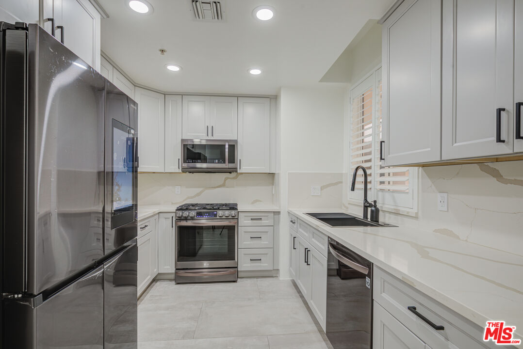 1444 South Point View Street, Unit 103 Los Angeles, CA 90035 - Photo 27 of 44 a kitchen with stainless steel appliances granite countertop a sink stove and refrigerator