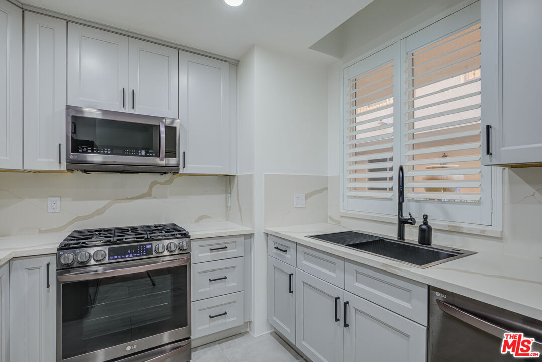 1444 South Point View Street, Unit 103 Los Angeles, CA 90035 - Photo 28 of 44 a kitchen with stainless steel appliances a stove a microwave and window