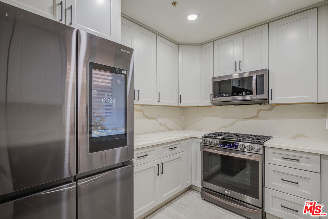 1444 South Point View Street, Unit 103 Los Angeles, CA 90035 - Photo 29 of 44 a kitchen with white cabinets and stainless steel appliances
