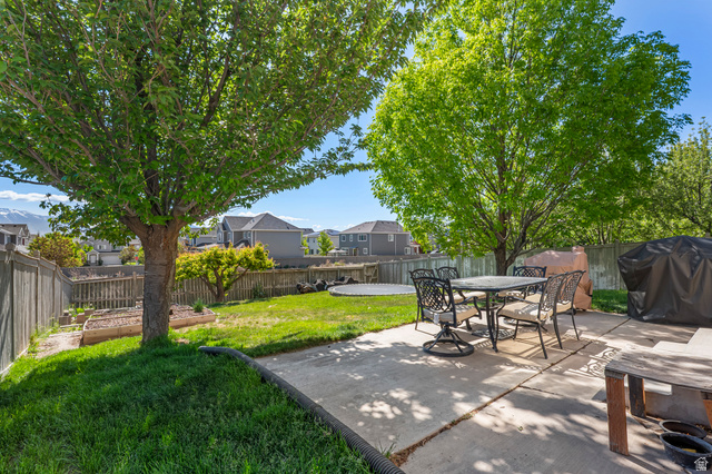 7092 Cherokee Street Eagle Mountain, UT 84005 - Photo 20 of 27 Expansive backyard featuring a concrete patio, mature trees, a manicured lawn, and raised garden beds