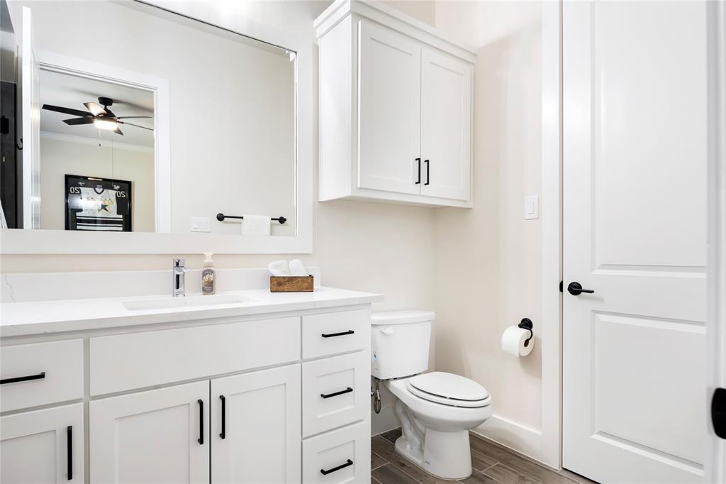 704 Abbey Road Van Alstyne, TX 75495 - Photo 30 of 38 a bathroom with a toilet sink vanity and mirror