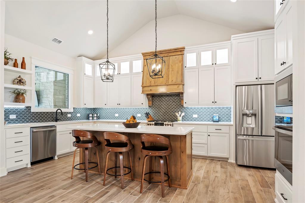 704 Abbey Road Van Alstyne, TX 75495 - Photo 6 of 38 a kitchen with stainless steel appliances granite countertop a sink a stove a refrigerator and island with wooden floor