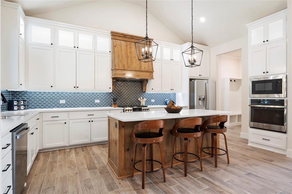 704 Abbey Road Van Alstyne, TX 75495 - Photo 7 of 38 a kitchen with stainless steel appliances granite countertop a sink a stove a refrigerator and island with wooden floor