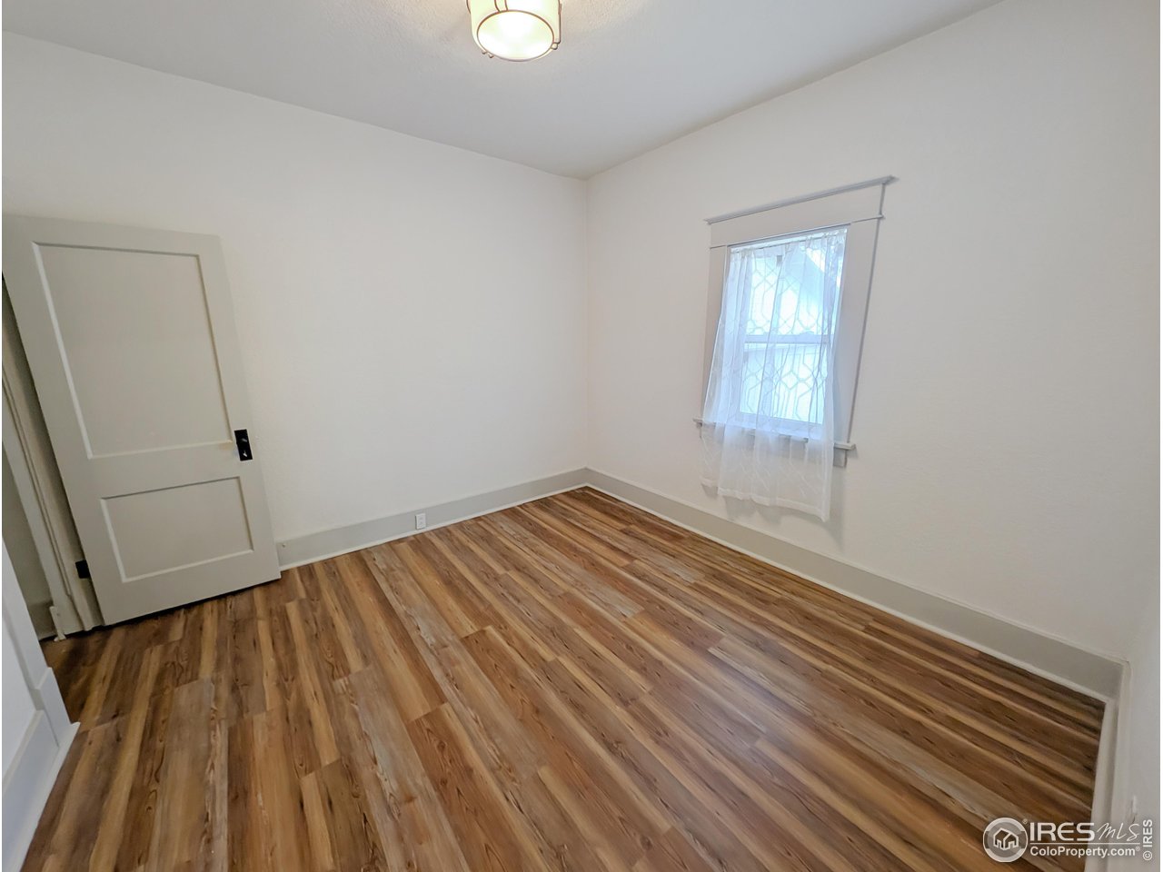 710 Carson Street Brush, CO 80723 - Photo 17 of 31 an empty room with wooden floor and windows