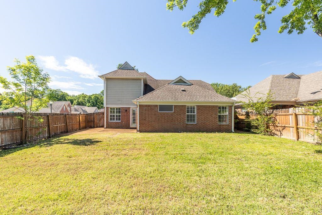 9768 Riggin Drive Memphis, TN 38002 - Photo 27 of 32 Expansive backyard featuring a manicured lawn, a full privacy fence, and a brick and siding exterior