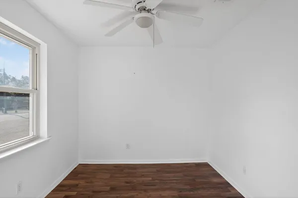a view of an empty room with wooden floor and a window