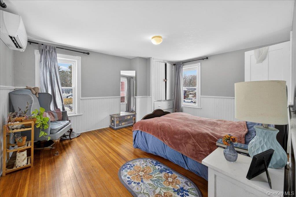 792 Springtown Road Rosendale, NY 12486 - Photo 16 of 45 Bedroom featuring a wainscoted wall, a wall unit AC, and wood-type flooring