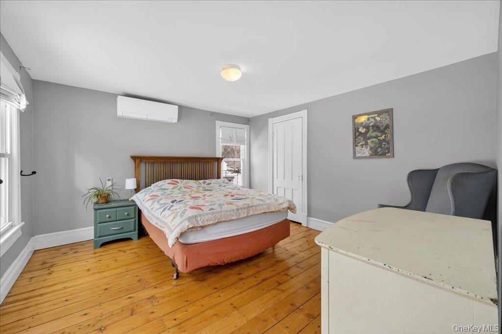 792 Springtown Road Rosendale, NY 12486 - Photo 19 of 45 Bedroom featuring light wood finished floors, a wall mounted AC, and a closet