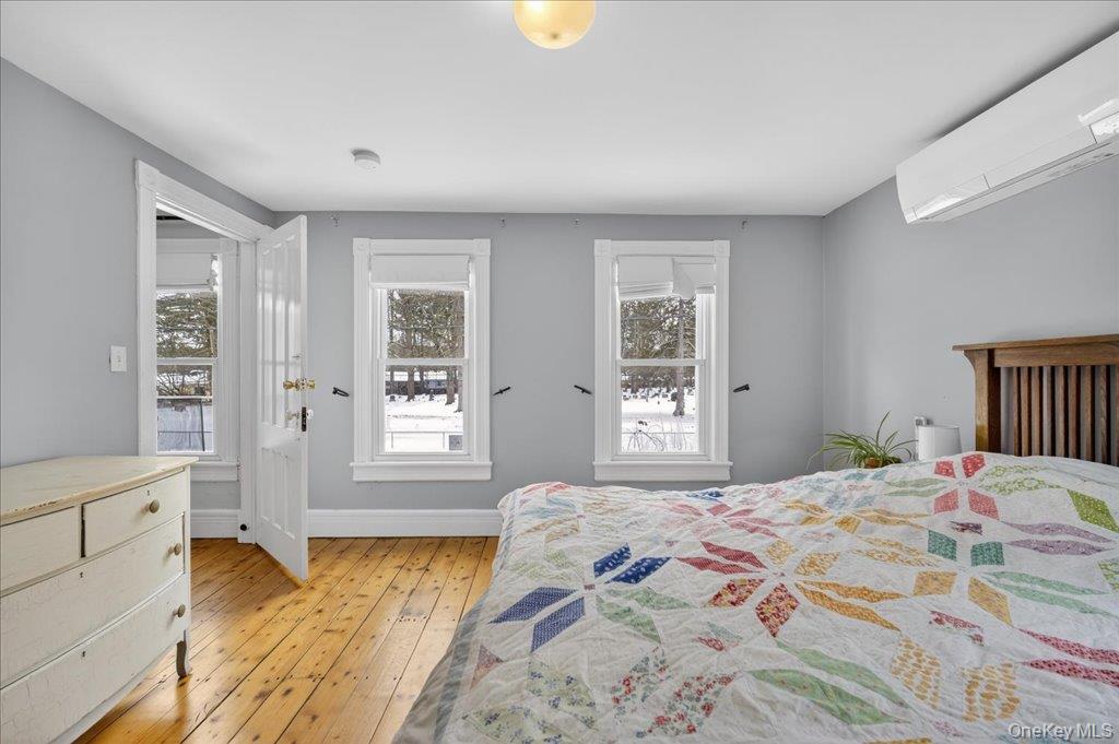 792 Springtown Road Rosendale, NY 12486 - Photo 21 of 45 Bedroom featuring a wall mounted AC, light wood finished floors, and multiple windows