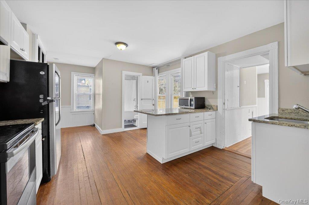 792 Springtown Road Rosendale, NY 12486 - Photo 26 of 45 Kitchen featuring light stone counters, a peninsula, white cabinetry, stainless steel appliances, and dark wood-style floors