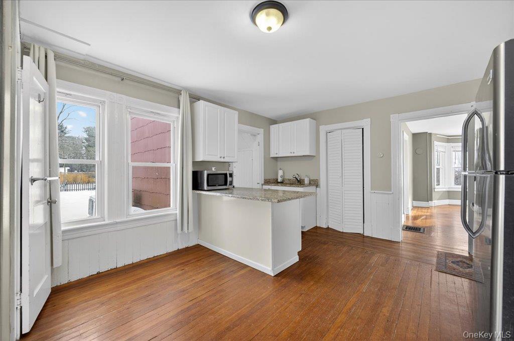 792 Springtown Road Rosendale, NY 12486 - Photo 28 of 45 Kitchen featuring white cabinets, appliances with stainless steel finishes, dark wood-style flooring, healthy amount of natural light, and wainscoting
