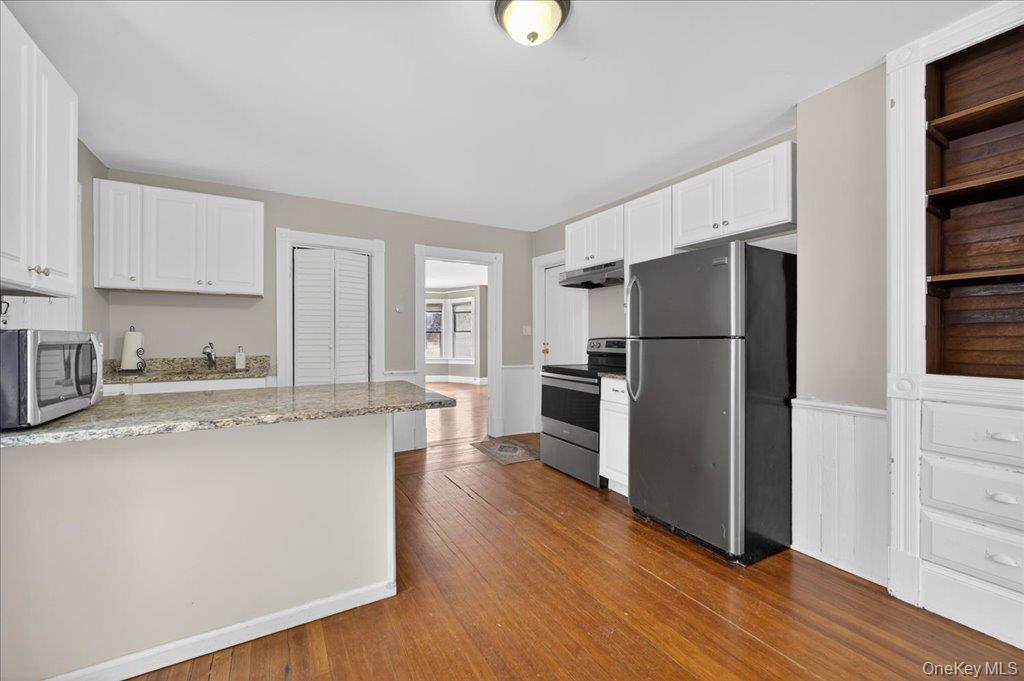 792 Springtown Road Rosendale, NY 12486 - Photo 29 of 45 Kitchen featuring appliances with stainless steel finishes, white cabinets, a peninsula, light stone counters, and dark wood finished floors