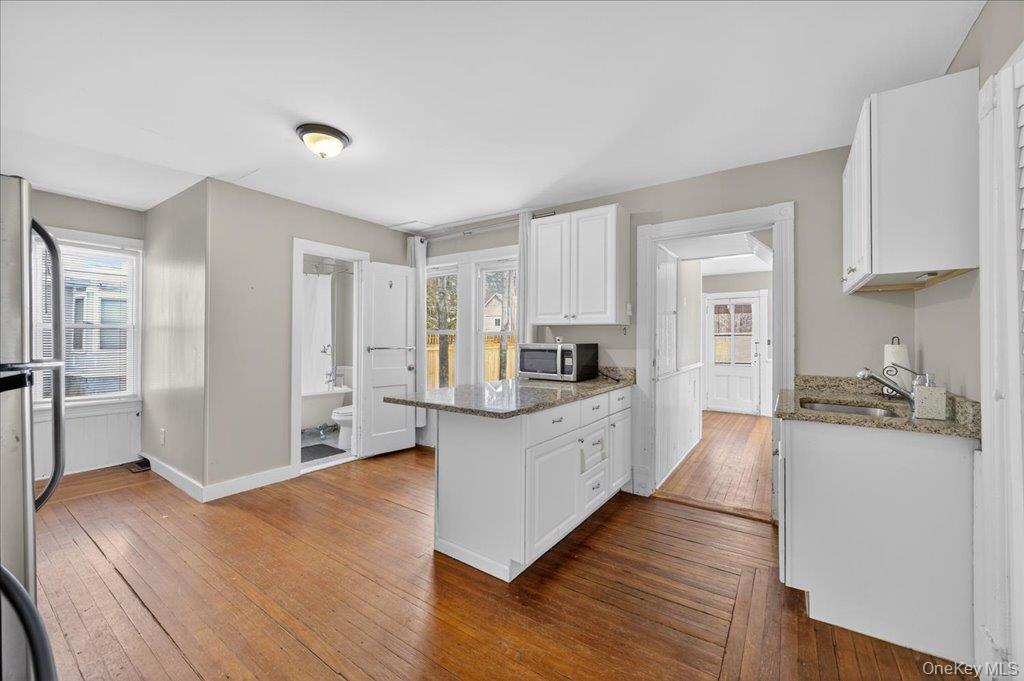 792 Springtown Road Rosendale, NY 12486 - Photo 32 of 45 Kitchen with a peninsula, light stone countertops, stainless steel appliances, and white cabinets