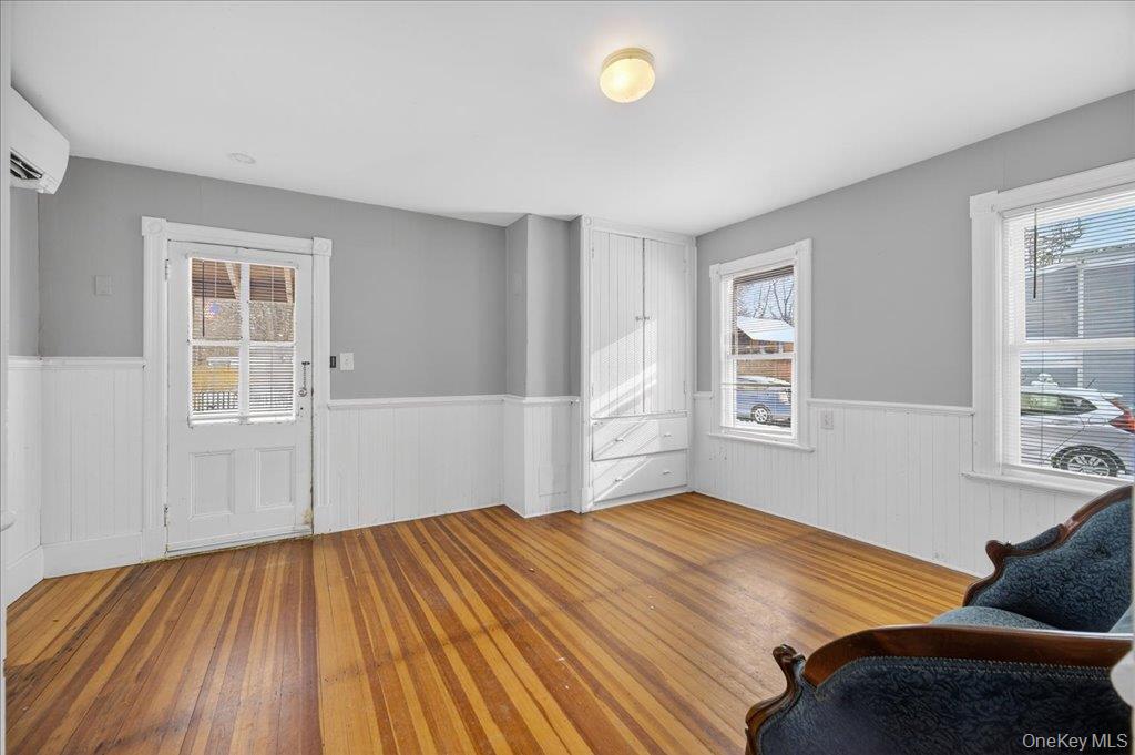 792 Springtown Road Rosendale, NY 12486 - Photo 37 of 45 Living area featuring wood-type flooring, plenty of natural light, a wall mounted air conditioner, and a wainscoted wall