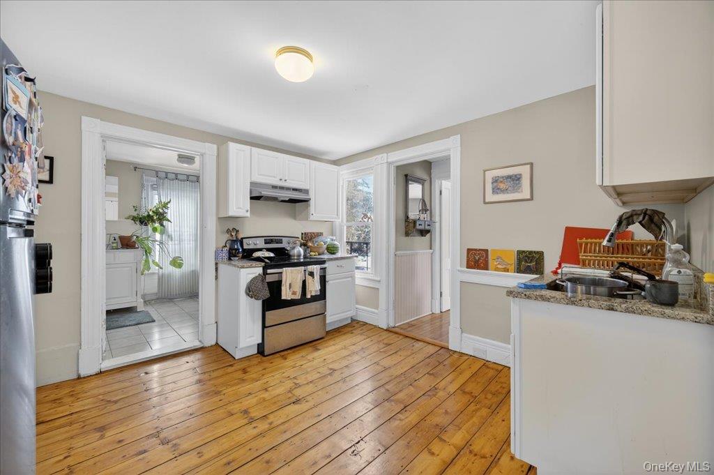 792 Springtown Road Rosendale, NY 12486 - Photo 7 of 45 Kitchen featuring stainless steel appliances, white cabinets, light wood finished floors, under cabinet range hood, and light stone countertops