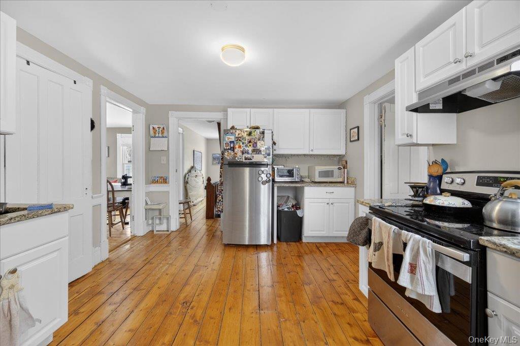 792 Springtown Road Rosendale, NY 12486 - Photo 9 of 45 Kitchen featuring stainless steel appliances, white cabinetry, under cabinet range hood, light wood-type flooring, and light stone counters