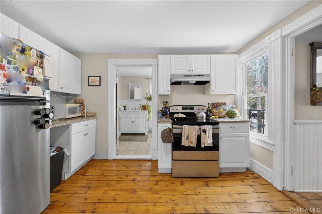 792 Springtown Road Rosendale, NY 12486 - Photo 10 of 45 Kitchen featuring appliances with stainless steel finishes, white cabinetry, under cabinet range hood, and light stone counters