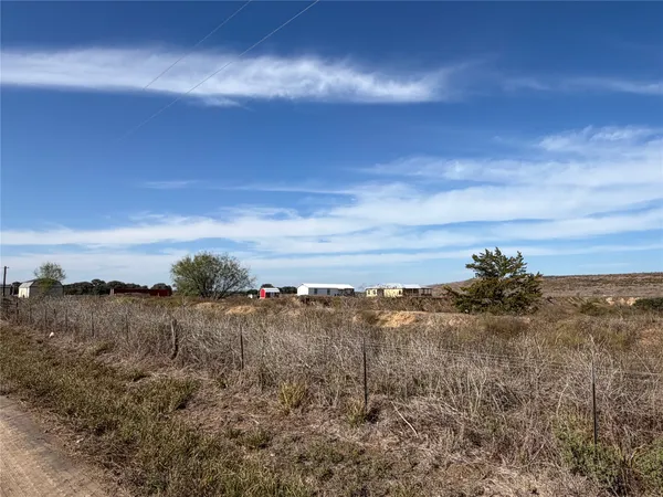 a view of a dry yard with wooden fence