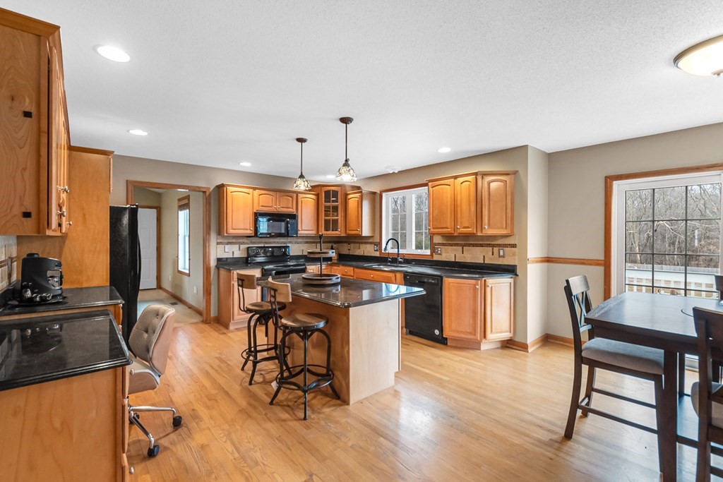 34 Schneider Road Somers, CT 06071 - Photo 10 of 42 a open kitchen with stainless steel appliances kitchen island granite countertop a stove a refrigerator a dining table and chairs with wooden floor