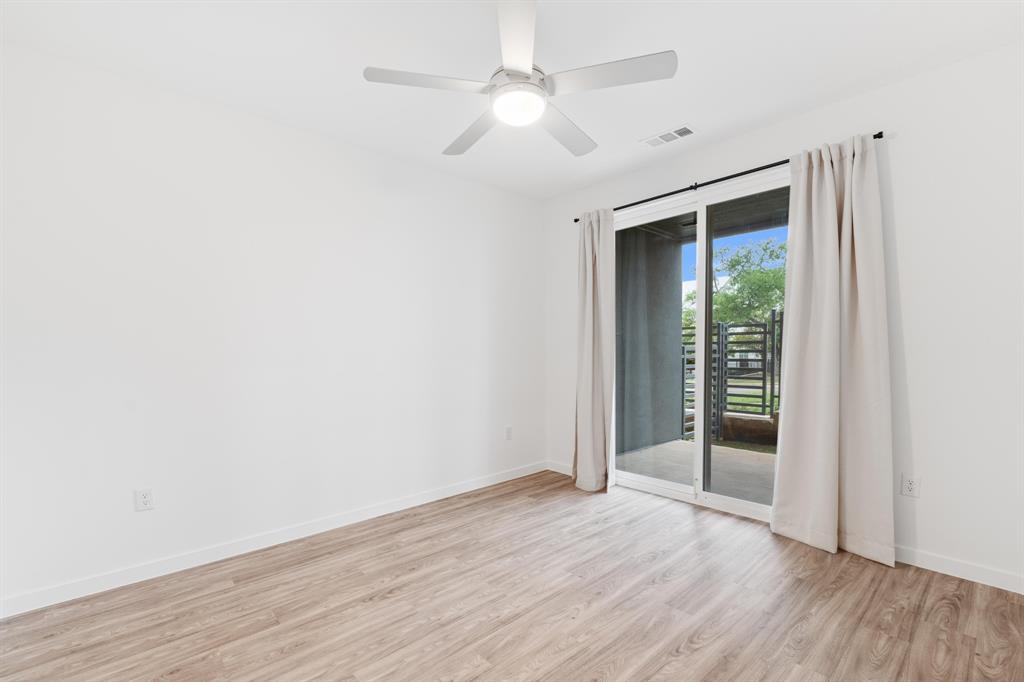 4801 Springdale Road, Unit 2010 Austin, TX 78723 - Photo 14 of 34 Spacious room featuring wood-finish flooring, a contemporary ceiling fan with integrated lighting, and a sliding glass door leading to an outdoor area