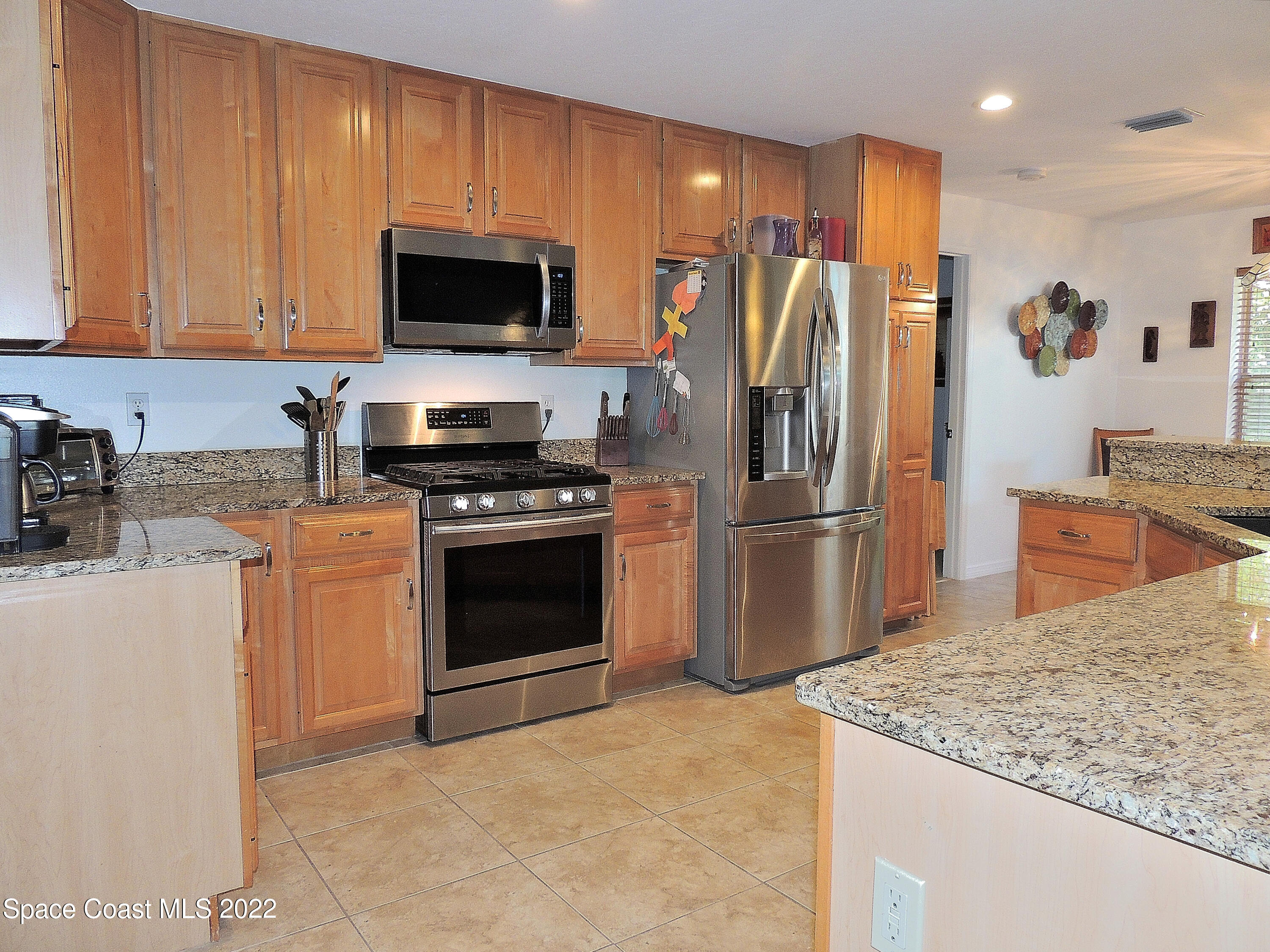 2473 Harlock Road Melbourne, FL 32934 - Photo 8 of 45 a kitchen with stainless steel appliances granite countertop a stove a refrigerator and a sink
