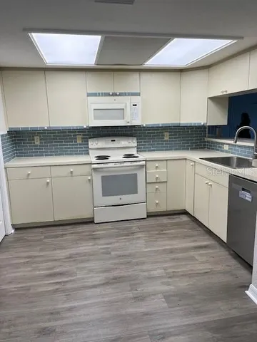 a kitchen with granite countertop stainless steel appliances cabinets a sink and a wooden floor