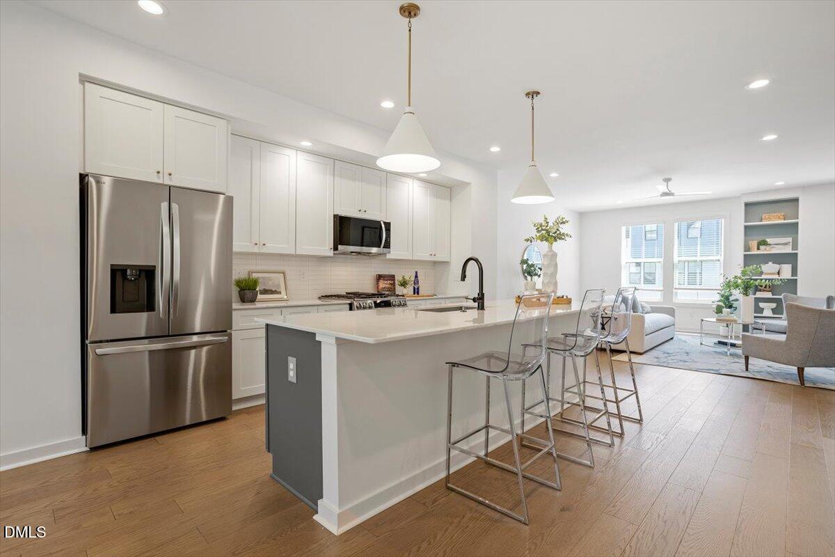 6419 Tanner Oak Lane Raleigh, NC 27613 - Photo 14 of 39 a kitchen with stainless steel appliances kitchen island granite countertop a refrigerator a stove a sink a dining table and chairs with wooden floor