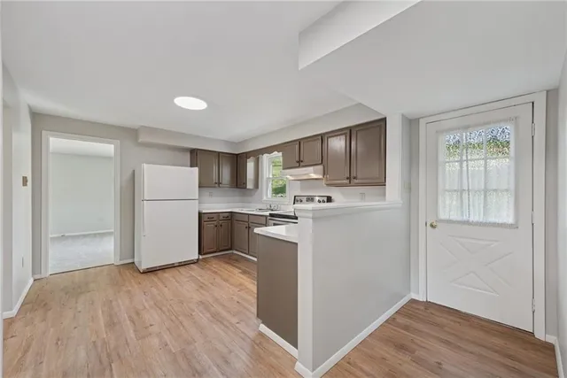 a kitchen with a refrigerator a stove top oven and wooden floor