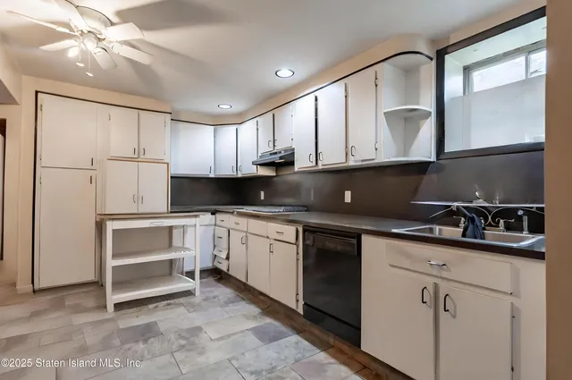 a kitchen with stainless steel appliances kitchen island granite countertop a refrigerator a sink dishwasher and a flat tv screen