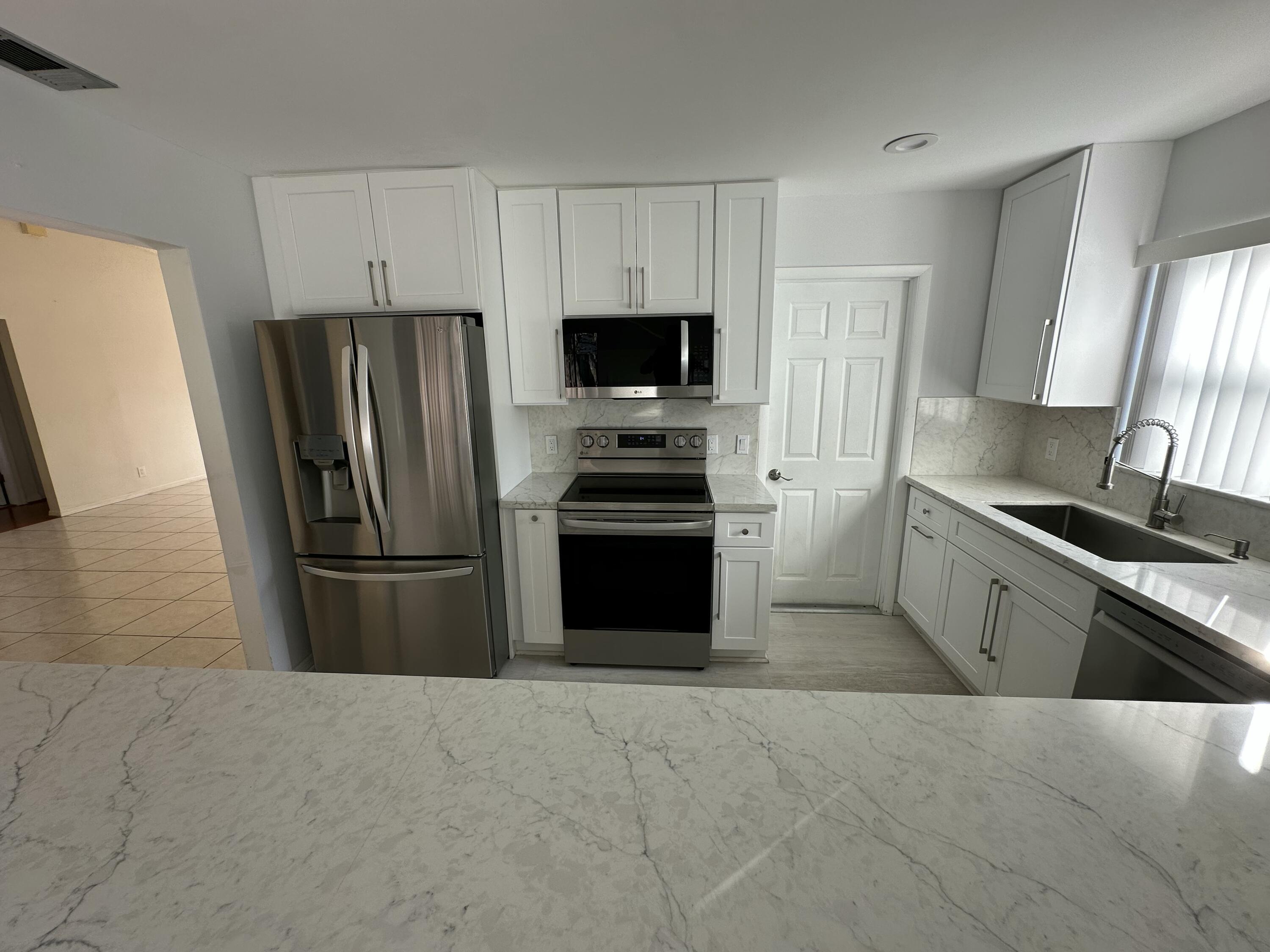3291 Southwest 4th Street Deerfield Beach, FL 33442 - Photo 14 of 38 a kitchen with a refrigerator and a stove top oven