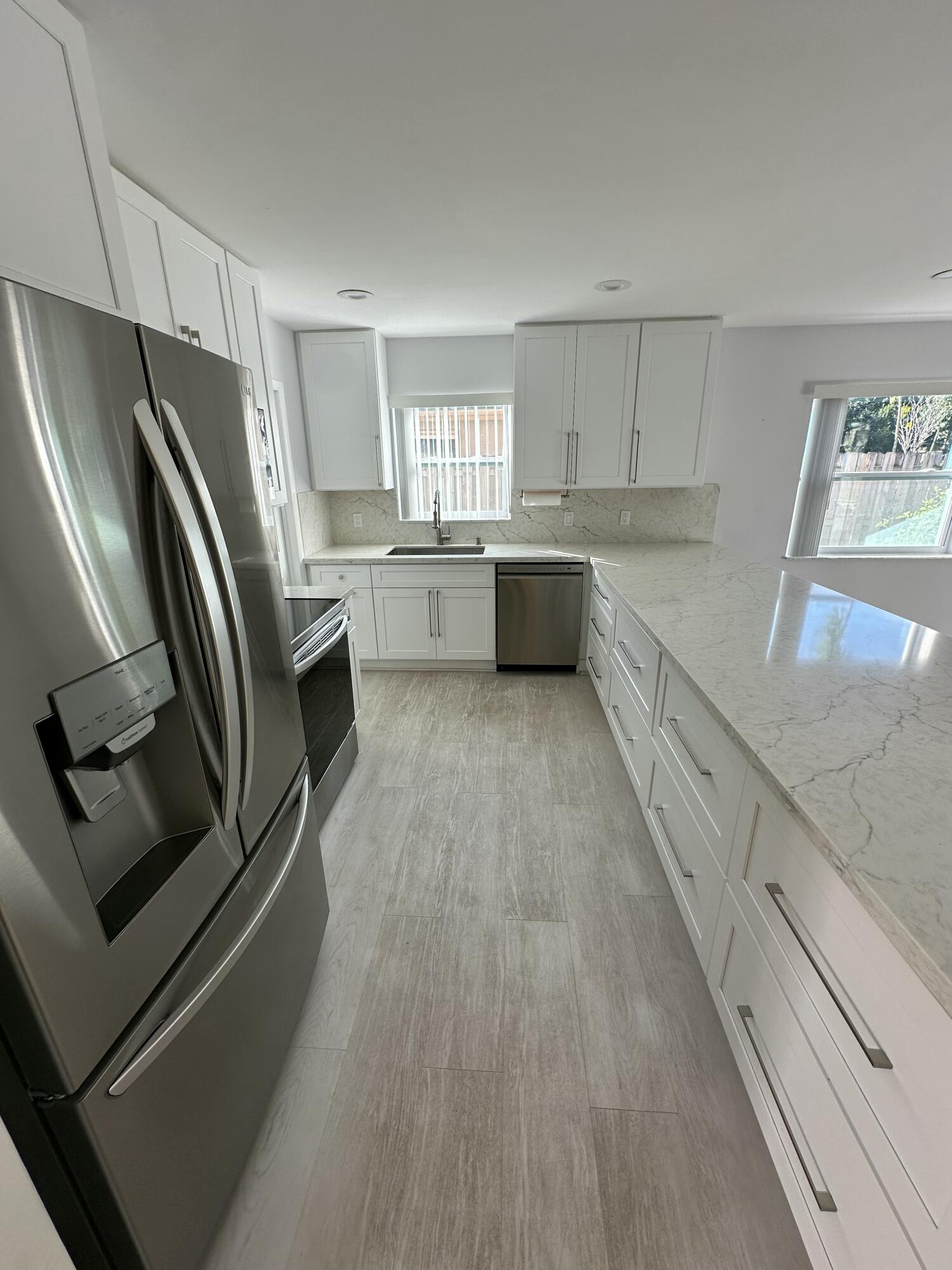 3291 Southwest 4th Street Deerfield Beach, FL 33442 - Photo 15 of 38 a kitchen with stainless steel appliances a refrigerator sink and white cabinets