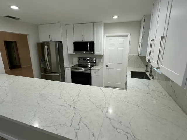 a kitchen with stainless steel appliances granite countertop a stove a sink and a refrigerator